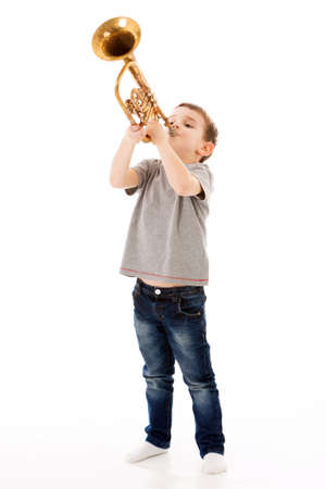 young boy blowing into a trumpet against white backgroundの写真素材