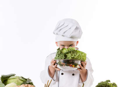 One little boy as chef cook making salad, cooking with vegetables. Isolated on white.の写真素材