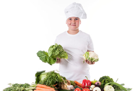 One little boy as chef cook making salad, cooking with vegetables. Isolated on white.の写真素材