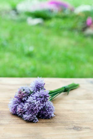 Flower chives tied in a snop on a natural wooden cutting boardの写真素材