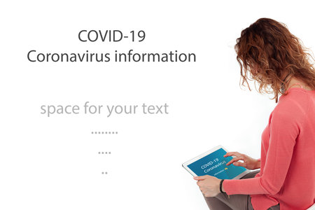 A woman looks into a tablet and watches information for coronavirus.
