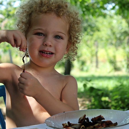 portrait of a happy little boy eating in the garden in summerの写真素材