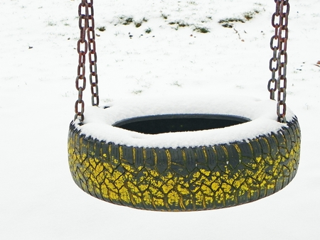 snowy tire swing on the empty playground in winterの写真素材