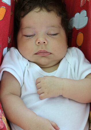 a closeup shot of a newborn baby sleeping in a hammockの写真素材
