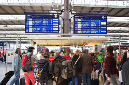MUNICH, GERMANY - NOVEMBER 8, 2014: Several people waiting in a train station for their train with the destination board in the backgroundのeditorial素材