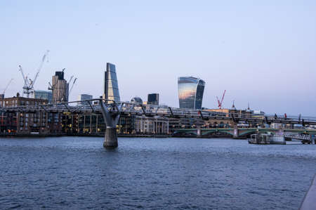 View of millennium bridge in London at evening with sun reflections in the Walkie Talkie and Cheesegrater buildingの写真素材