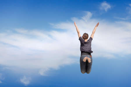 young woman jumping on the blue skyの写真素材