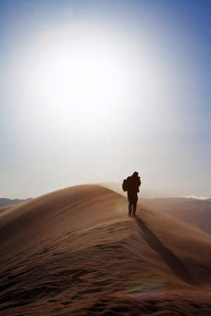 man walking on a sand dunes in the desertの写真素材