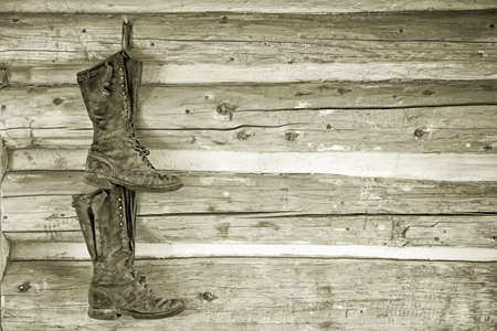 a pair of boots hanging from a wooden wall in a rustic cottageの写真素材
