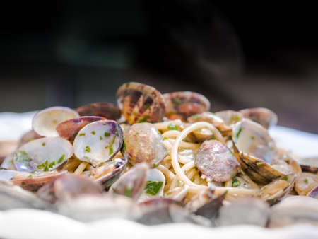 Serving of clams and savory sauce garnished with chopped parsley on Italian pasta or noodles in a low angle view on the plateの写真素材