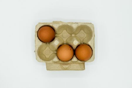 Three Organic chicken eggs in a paper carton isolated on white backgroundの写真素材