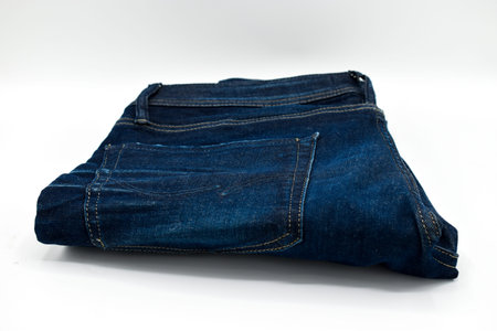 A pair of folded blue skinny jeans on a white backgroundの写真素材