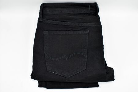 A pair of folded black skinny jeans on a white backgroundの写真素材