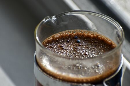 A close up of a cafetiere brewing coffee on a kitchen window ledgeの写真素材