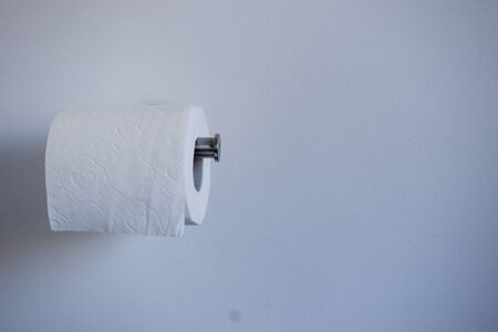 Toilet paper on a holder against a white wall. Toilet paper panic buying, hoarding conceptの写真素材