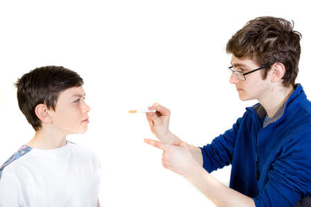 Older brother bullying younger brother to smoke against his willの写真素材