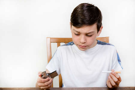 Young boy thinking about smoking a cigarette holding a lighterの写真素材