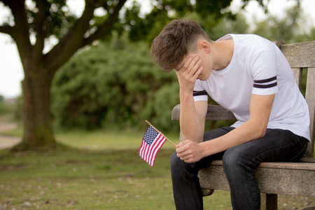 Depressed teenage boy with United States Flagの写真素材
