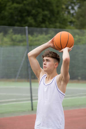 Teenage boy shooting a hoop on a basketball courtの写真素材