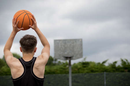 Teenage boy shooting a hoop on a basketball courtの写真素材