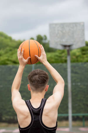 Teenage boy shooting a hoop on a basketball courtの写真素材