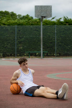 Teenage boy sitting on a  basketball courtの写真素材