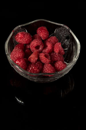 Raspberries in a glass bowl isolated on a black backgroundの写真素材