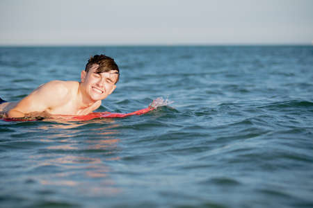 Teenage boy with a body board in the seaの写真素材