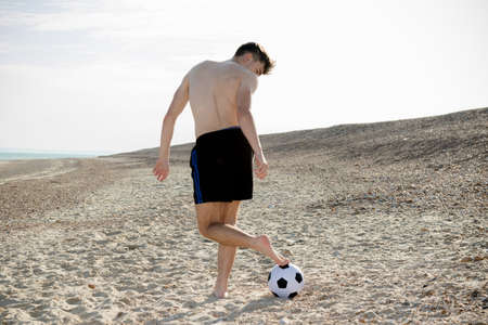 Teenage boy playing with a football on a beachの写真素材