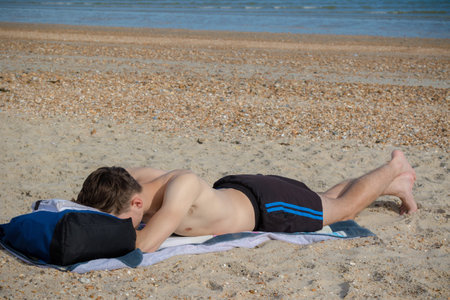 Teenage boy laying on a stoney beach