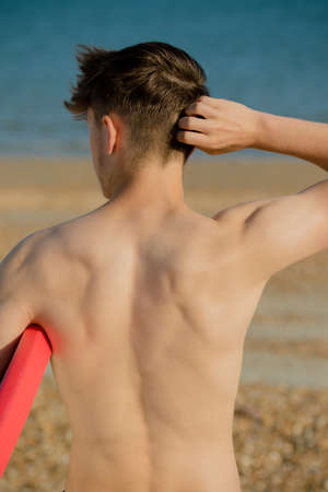 Teenage boy holding a body board on a beachの写真素材