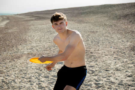 Teenage boy playing with a frisbee on a beachの写真素材