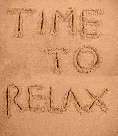 Time to relax written in soft wet sand on a beachの写真素材