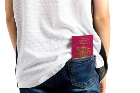 Young teenage boy isolated on white with a British passport in his pocketの写真素材