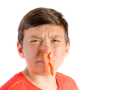 Young teenage boy isolated on a white background with a clothes peg on his noseの写真素材