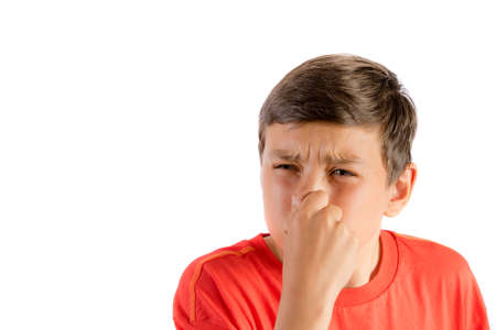 Young teenage boy isolated on a white background holding his noseの写真素材