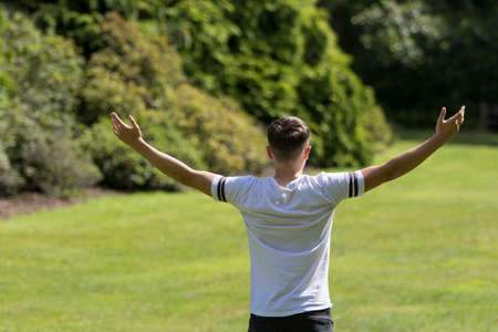 Teenage boy with his arms outstreched on a summer's dayの写真素材