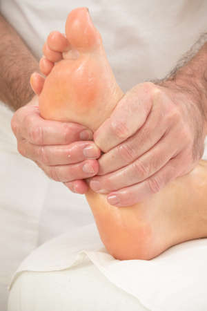 Teenage boy laying on a massage table, having a foot massageの写真素材