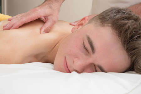 Teenage boy laying on a massage table, having a back massageの写真素材