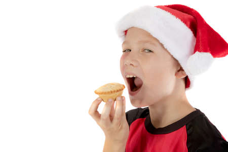 Pre-teen boy in christmas hat and a mince pieの写真素材