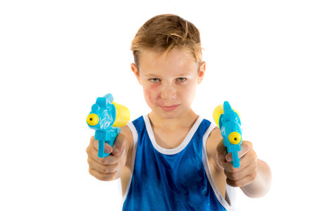Pre-teen boy playing with water pistols isolated on a white background