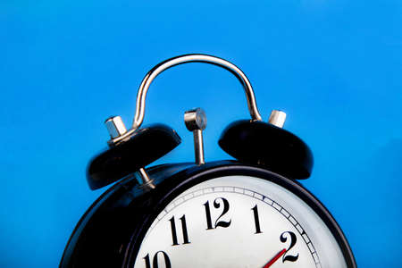 Black alarm clock with a blue background showing timeの写真素材