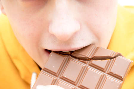 Close up of a young adult male eating chocolateの写真素材