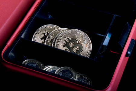 A bitcoin concept of bitcoins in a money box next to regular one poiund coinsの写真素材