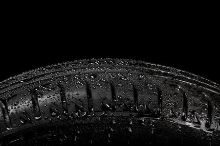 Close up view of a car tyre isolated on a black background with water drops