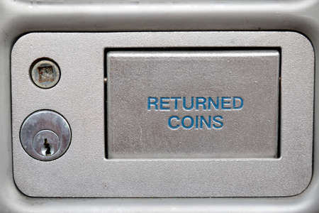 The flap to retrieve returned coins on a public phone boxの写真素材