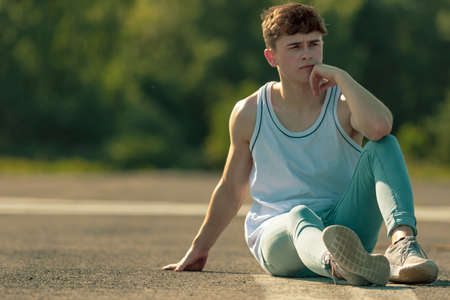 Young adult male sitting outside in the sunの写真素材