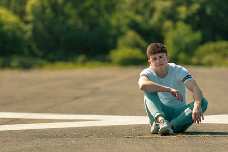 Young adult male sitting outside in the sunの写真素材