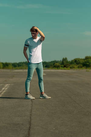 Young adult male standing outside in the sunの写真素材