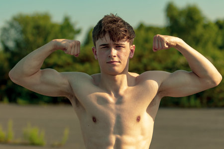 Young adult male flexing his muscles shirtless on a warm summer's day
